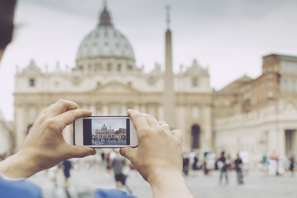 Sightseer taking pictures in Vatican Rome, Italy - September 2, 2015: Young man is taking pictures about the St. Peter's Basilica. Rome,